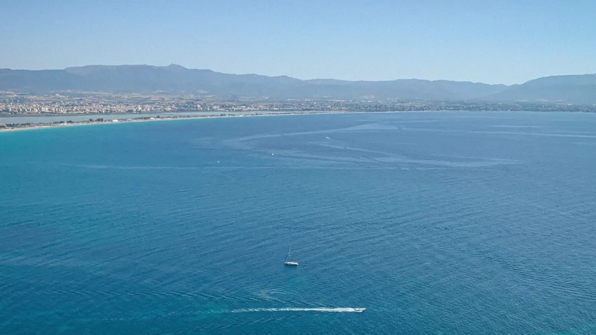 Shoreline of the Gulf of Cagliari with clear turquoise water seen from the sailing catamaran tour