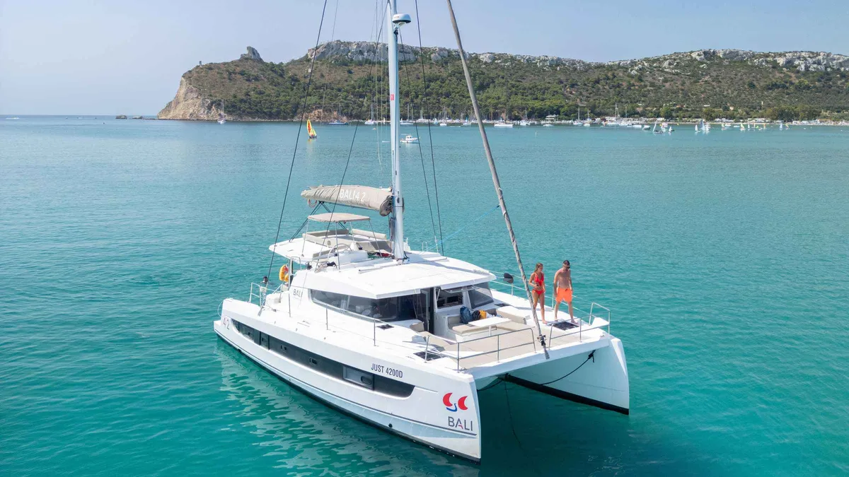 Sailing catamaran under way off the Poetto beach with Cagliari's skyline behind on a Gulf of the Angels boat tour, Sardinia