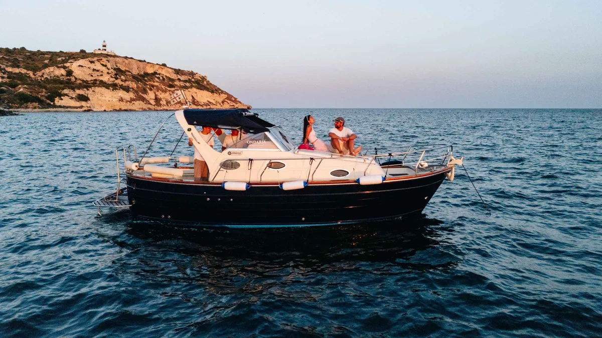 Traditional wooden gozzo boat anchored in a hidden cove with clear water on a private Cagliari boat charter, Sardinia